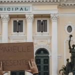 Crowd holding a sign 'MARIELLE PRESENTE' at Rio's city hall.